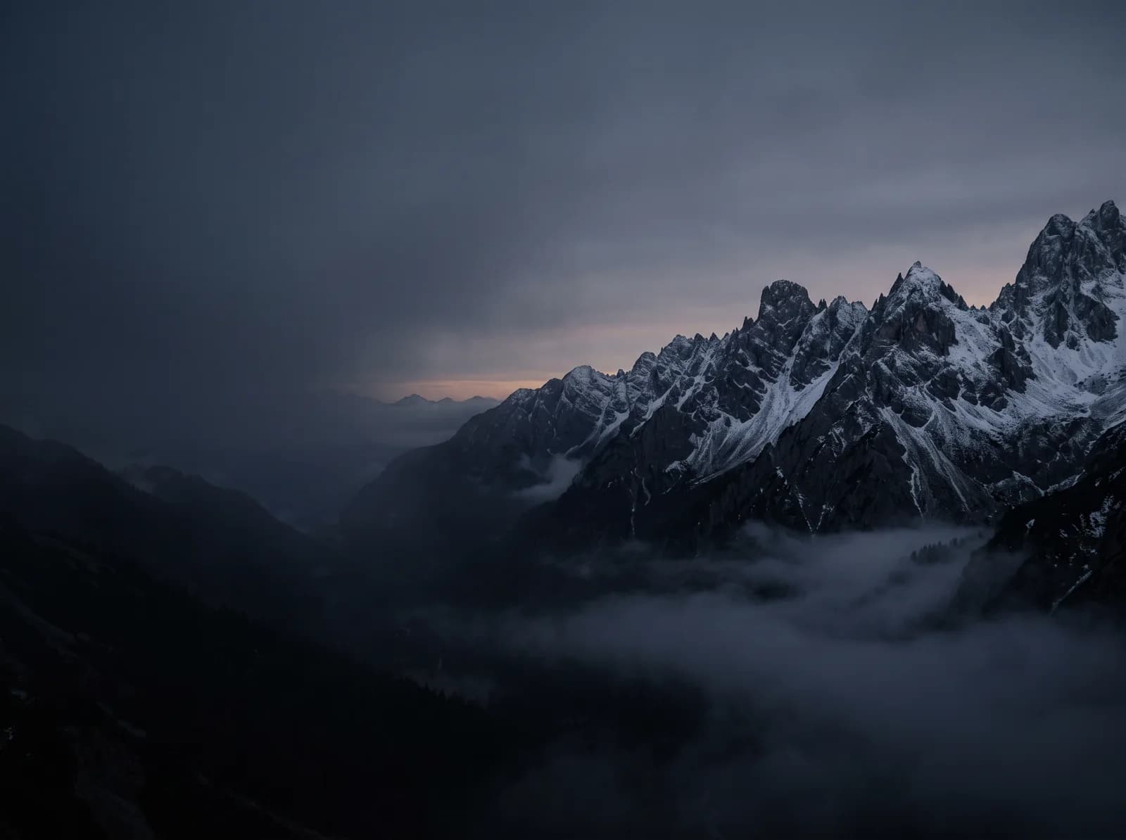 Snow-dusted mountain peaks above a misty valley at dusk